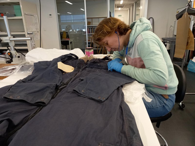  Senior Conversation Technician removing corrosion from the coveralls, The Museum of Transport and Technology (MOTAT).