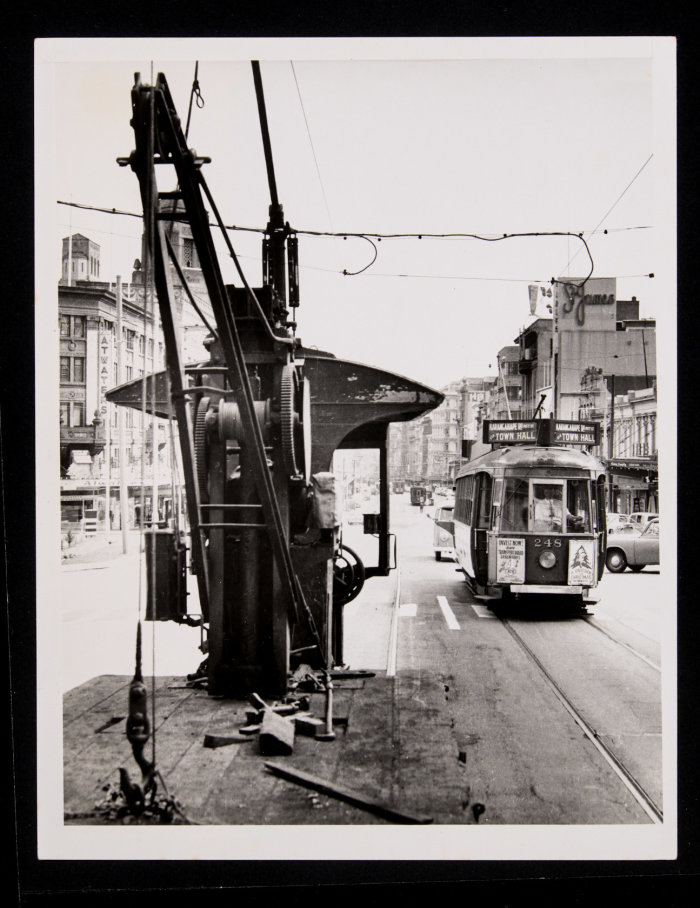 Graham Stewart. 1950s. Flat deck crane tram 304 about to pass tram 248 in Queen Street by Auckland Town Hall. No.304 was used to move track, poles and to repair safety zones in the city. PHO-2020-19.618. Walsh Memorial Library, The Museum of Transport and Technology (MOTAT). 
