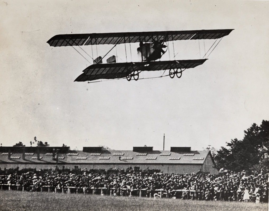 J.W.H.Scotland in low flight with spectators viewing below at Wigram. Whites Aviation Collection, Walsh Memorial Library, MOTAT, 15-1336