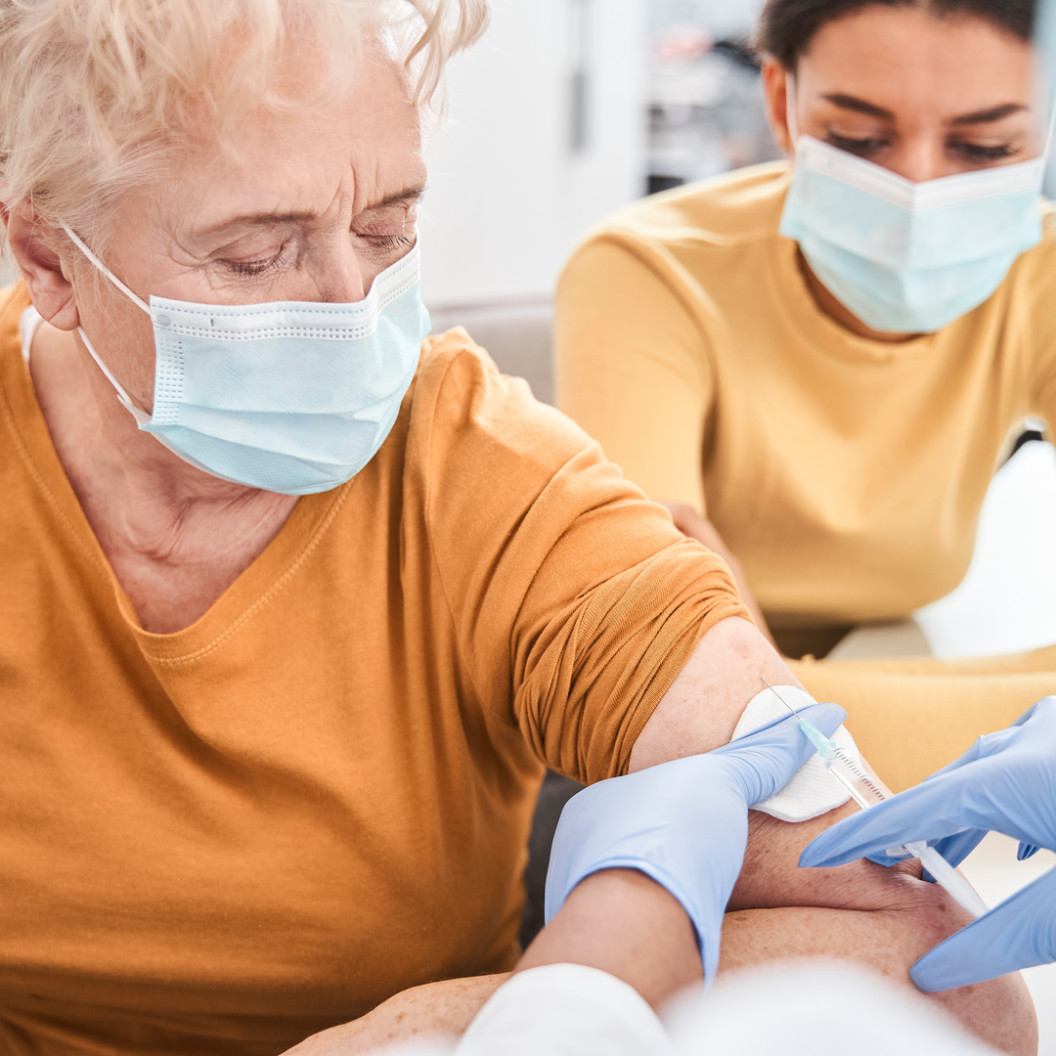 square-looking-at-doctor.-senior-female-pensioner-wearing-protective-mask-looking-at-doctor-in-blue-gloves-making-injection.-positive-delighted-patient-and-nurse-looking-at-each-other.-s