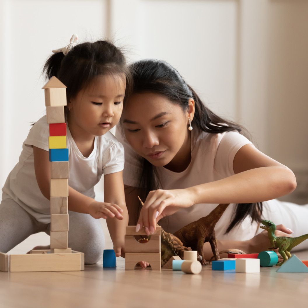 square-involved-little-daughter-and-her-mother-play-on-warm-floor-using-wooden-colorful-blocks-create-towers-and-buildings-improve-fine-motor-skill-of-kid.-funny-educational-games-for-ch