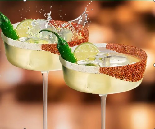 Two margarita glasses filled with a refreshing cocktail, garnished with lime wedges and whole green chili peppers.