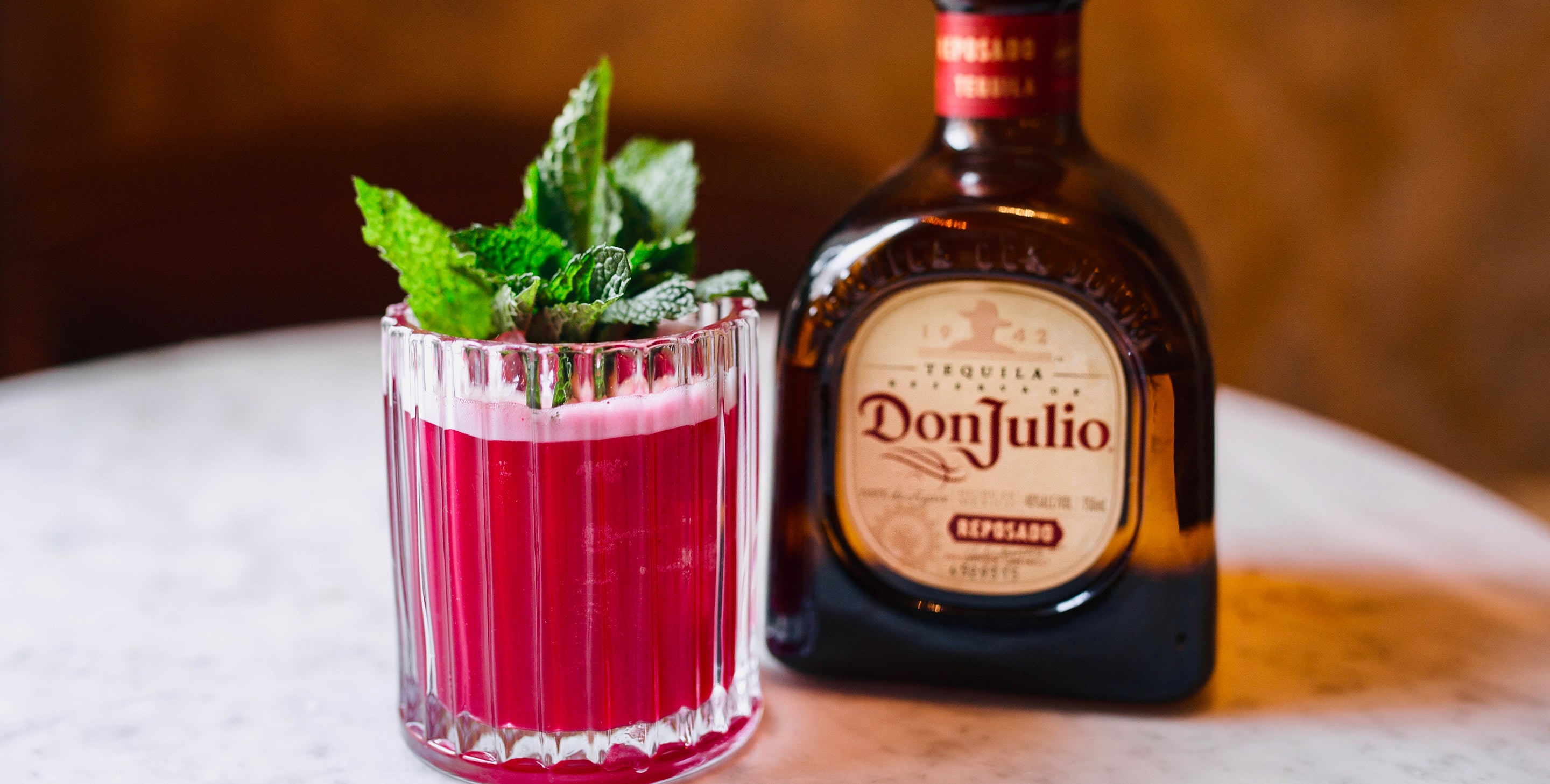 A glass of Beet Margarita next to a bottle of Don Julio Reposado