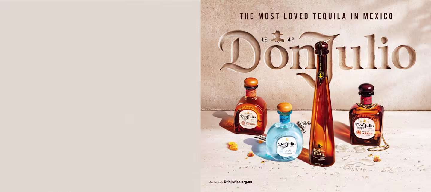 Image featuring a collection of Don Julio Tequila bottles displayed against a textured wall with the engraved text 'Don Julio 1942' and the slogan 'The Most Loved Tequila in Mexico.