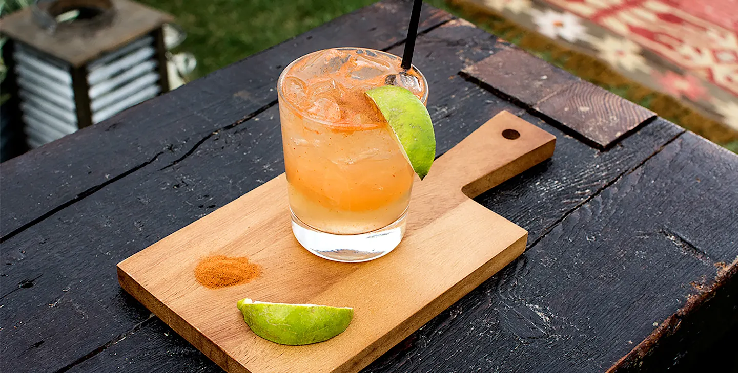 Añejo Spicy Margarita drink on a cutting board with two lime halves