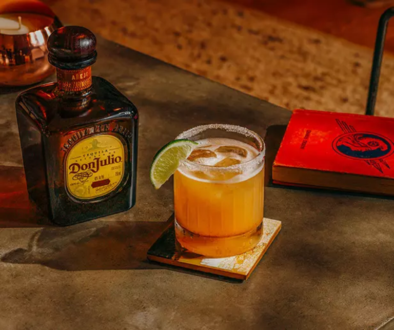 Añejo Spicy Margarita drink on a cutting board with two lime halves