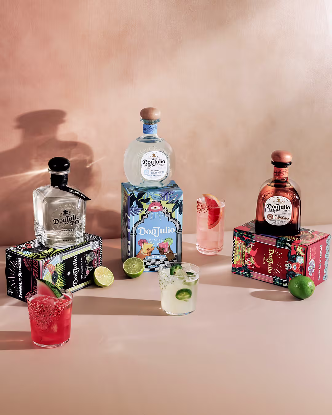 A lineup of special edition Don Julio 70, Don Julio Blanco, and Don Julio Reposado bottles with cocktails next to each bottle