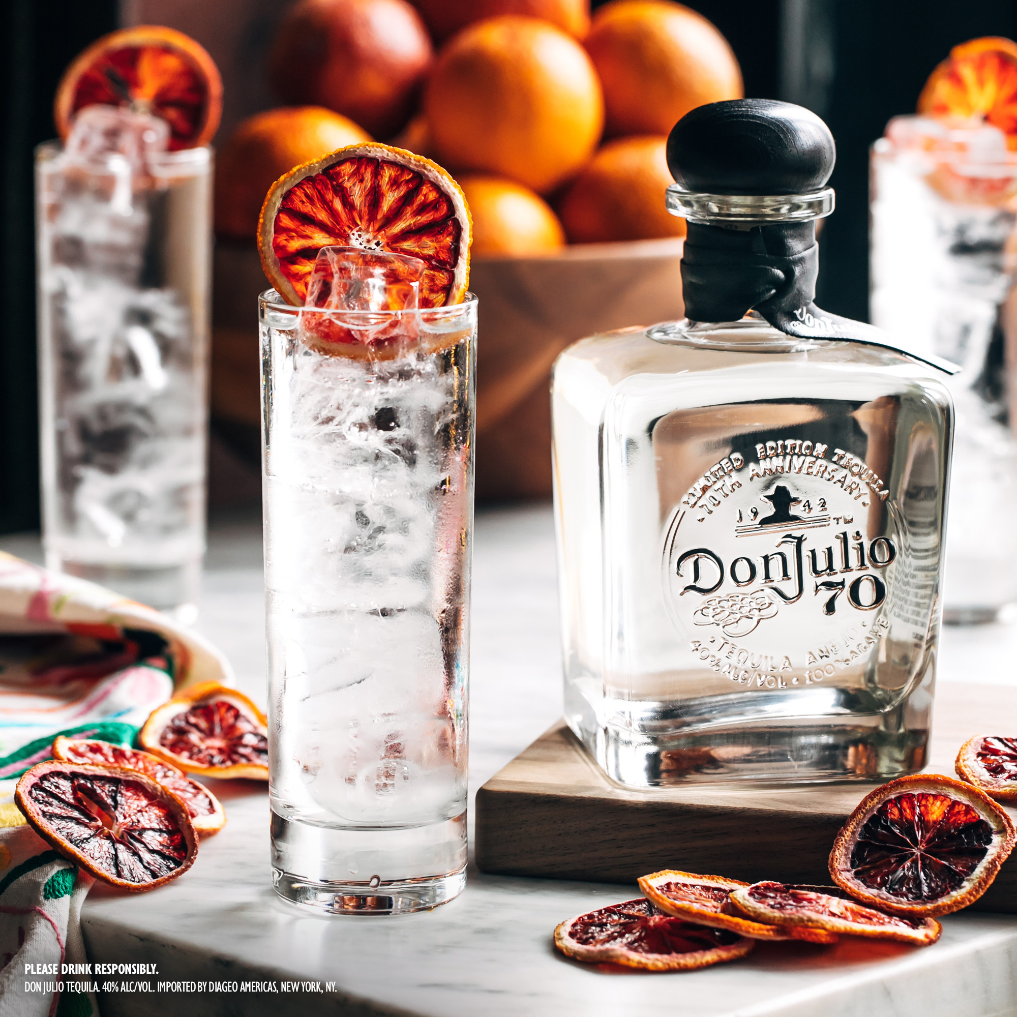 Una botella de Don Julio 70 en una bandeja decorada junto a varias mitades de limas