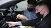 Two men checking the infotainment screen inside a car