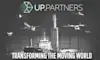 上部にUP.Partnersのロゴがあり、飛行機、ドローン、船、ロケット、車などのさまざまな交通手段が描かれたグレースケールの画像。下部には「動く世界を変革する」というテキストが表示されています。