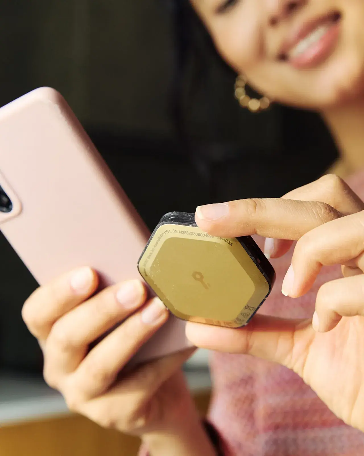 A smiling woman holding a phone and bitkey next to each other