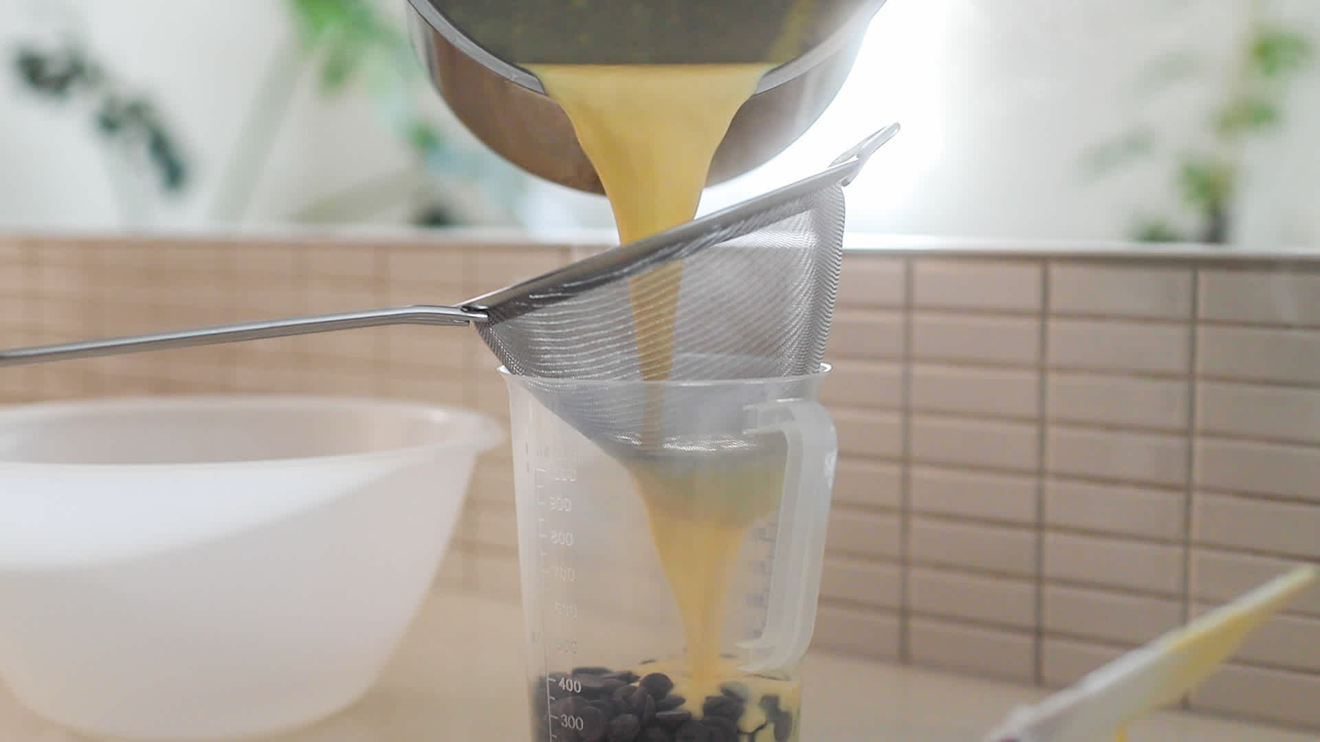 Pouring creme anglaise through sieve over chocolate