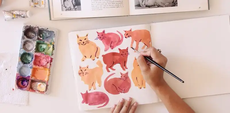 person drawing cats in sketchbook