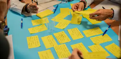 People in a room brainstorming shows how OKRs start in a room. not on just paper. 