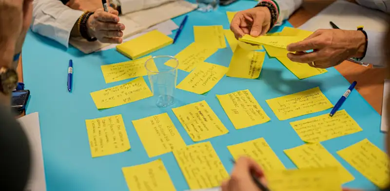 People in a room brainstorming shows how OKRs start in a room. not on just paper. 