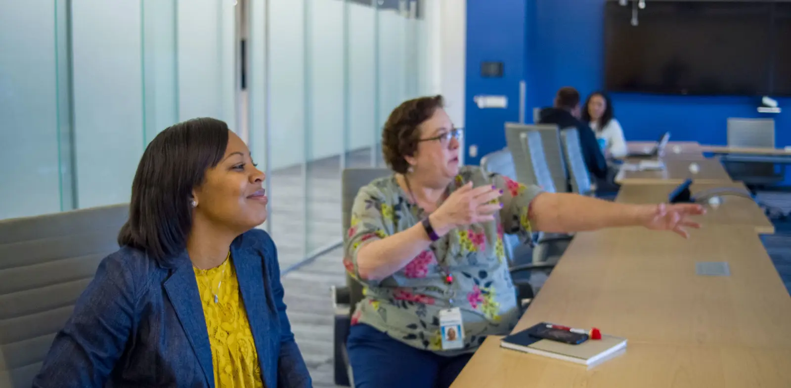 conversation between two women in a meeting room, caremore employees okr meeting