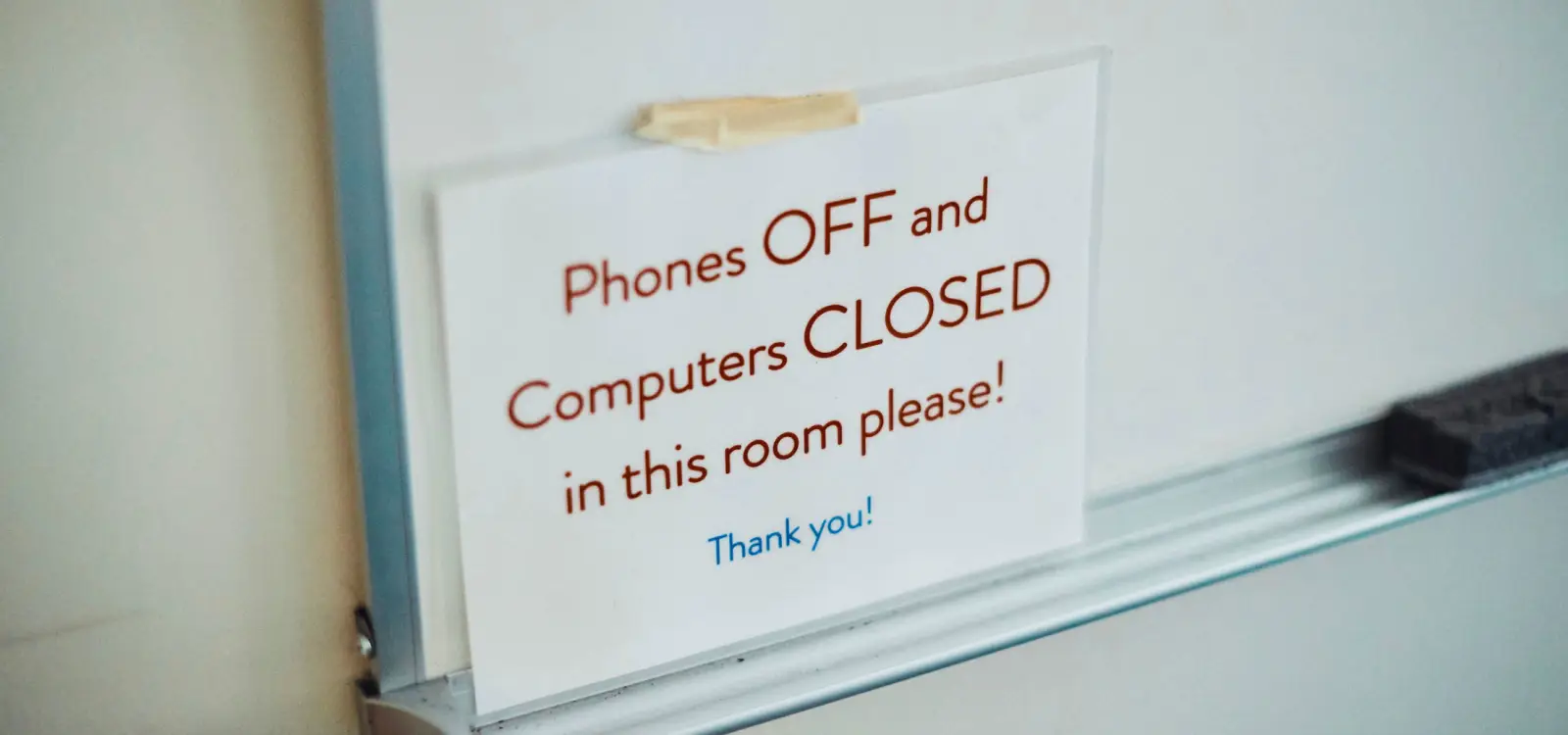 a sign on a whiteboard at apartment therapy that says phones off and computers closed in this room