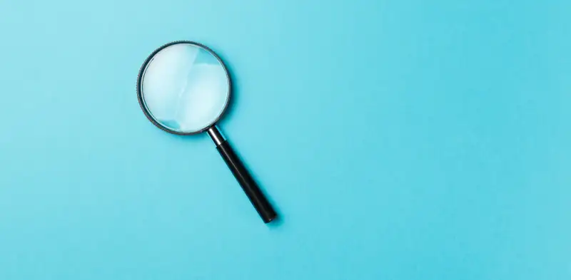 magnifying glass on blue background, finding the why of your company with okrs