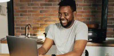 man on laptop in front of brick wall