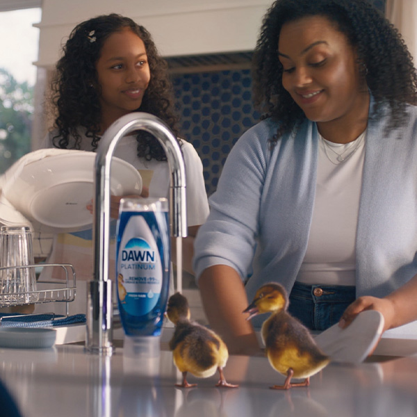 Madre e hija lavando los platos en la cocina.   