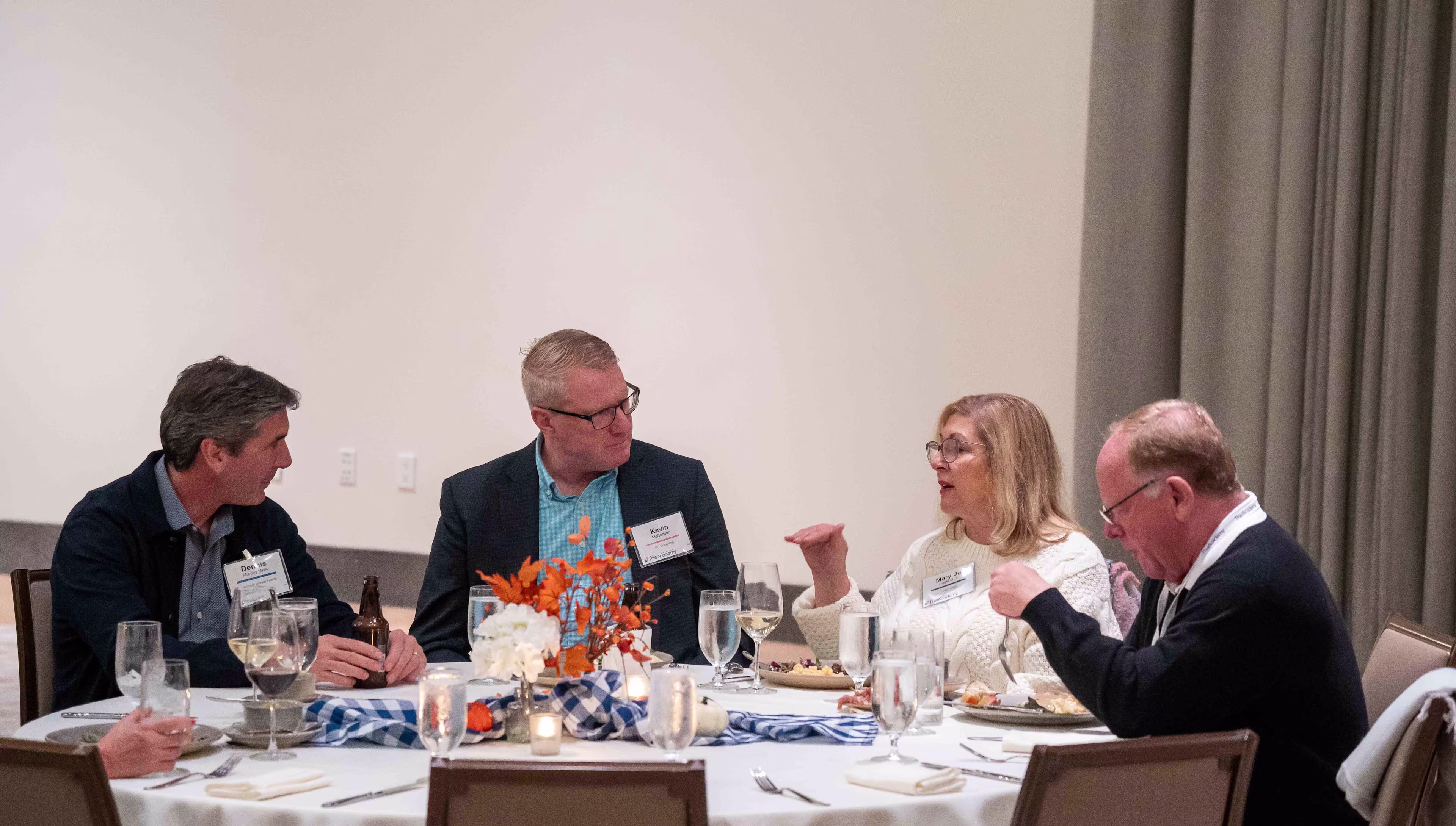 Attendees engage in conversation at a formal dinner session during healthcare technology conferences, surrounded by table décor and glassware.