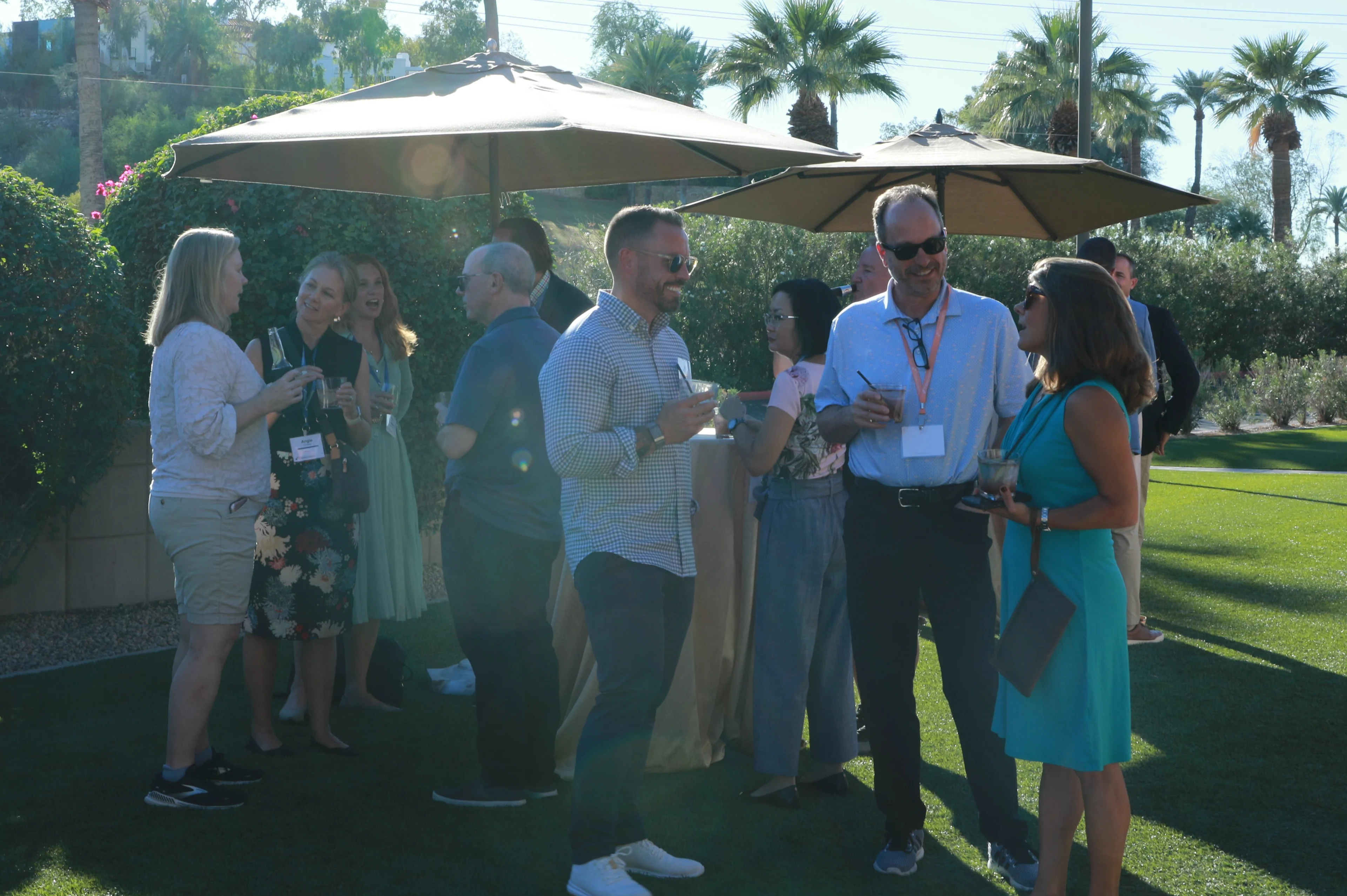 Attendees of the Pharmacy Growth Collaborative gathered outdoors socializing under large patio umbrellas. 
