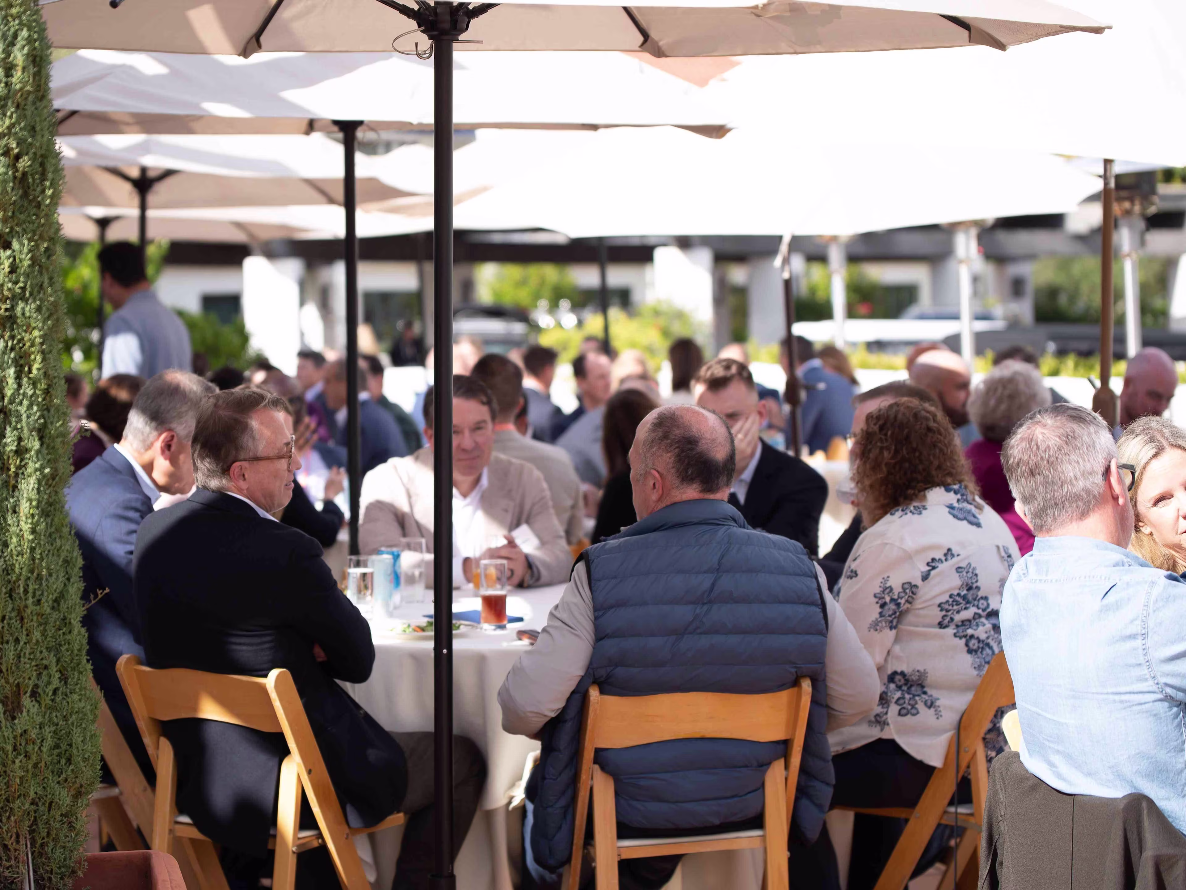 Attendees gather outdoors for networking conversations during healthcare medical conferences, seated at round tables under umbrellas.