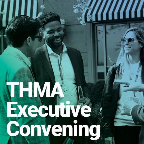 Three professionals engaged in an outdoor conversation during a THMA Executive Convening event, standing in front of a building with striped awnings. The overlay text reads “THMA Executive Convening.”