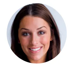 A smiling woman with long dark brown hair and a light complexion poses for a professional headshot against a plain background.