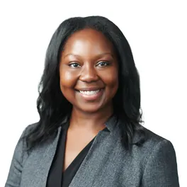 A woman wearing a gray blazer and black blouse smiling.
