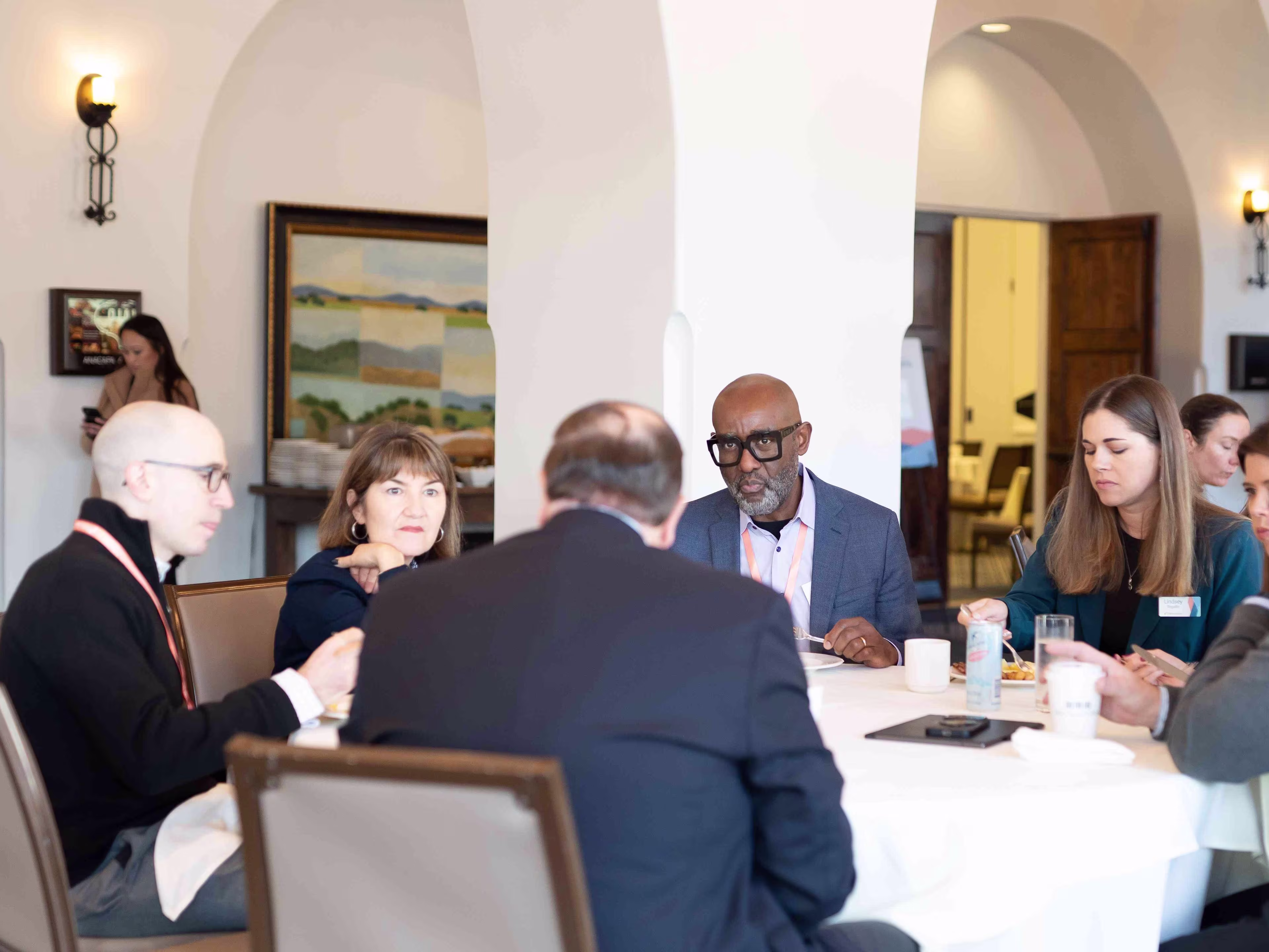 Executives participate in a round-table discussion during healthcare executive leadership conferences inside a bright, arched meeting space.