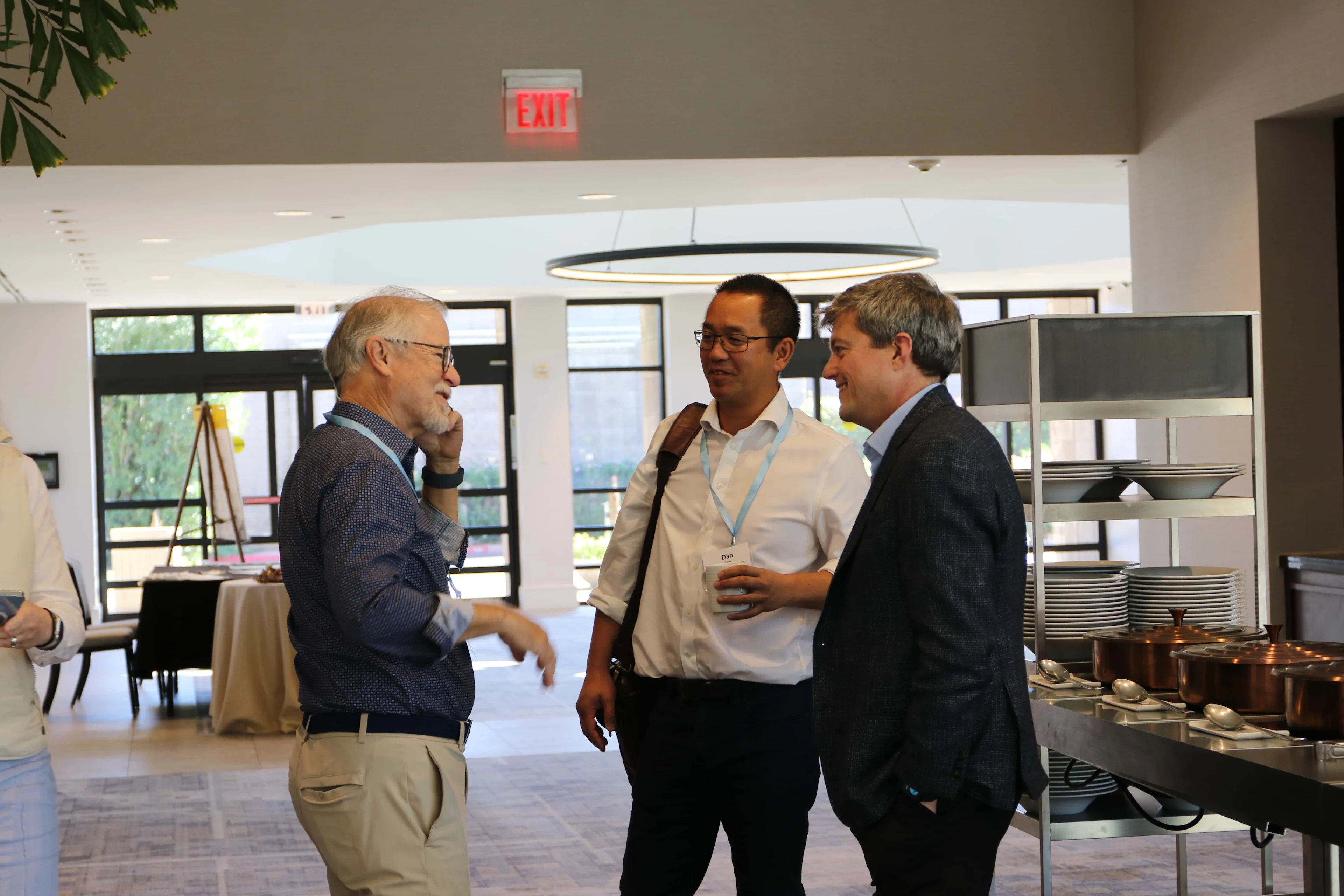 Three healthcare professionals engaging in a networking session and discussing industry trends in the lobby of a medical device conference.