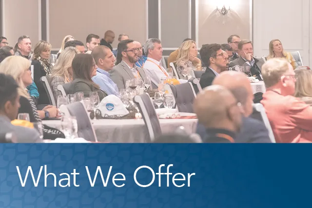  Image showing a large audience of professionals seated at tables during a formal event or conference. The lower third of the image features a blue banner with the text “What We Offer” in white font, suggesting a focus on value or services provided by the hosting organization.







