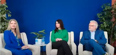Three healthcare leaders sit in white chairs against a blue background during a panel discussion, with two women on the left and center and a man on the right, discussing innovation in clinical practices.