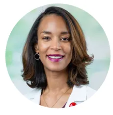 A woman with shoulder-length hair, wearing a white coat and hoop earrings, smiles in a professionally taken headshot framed in a circular crop.