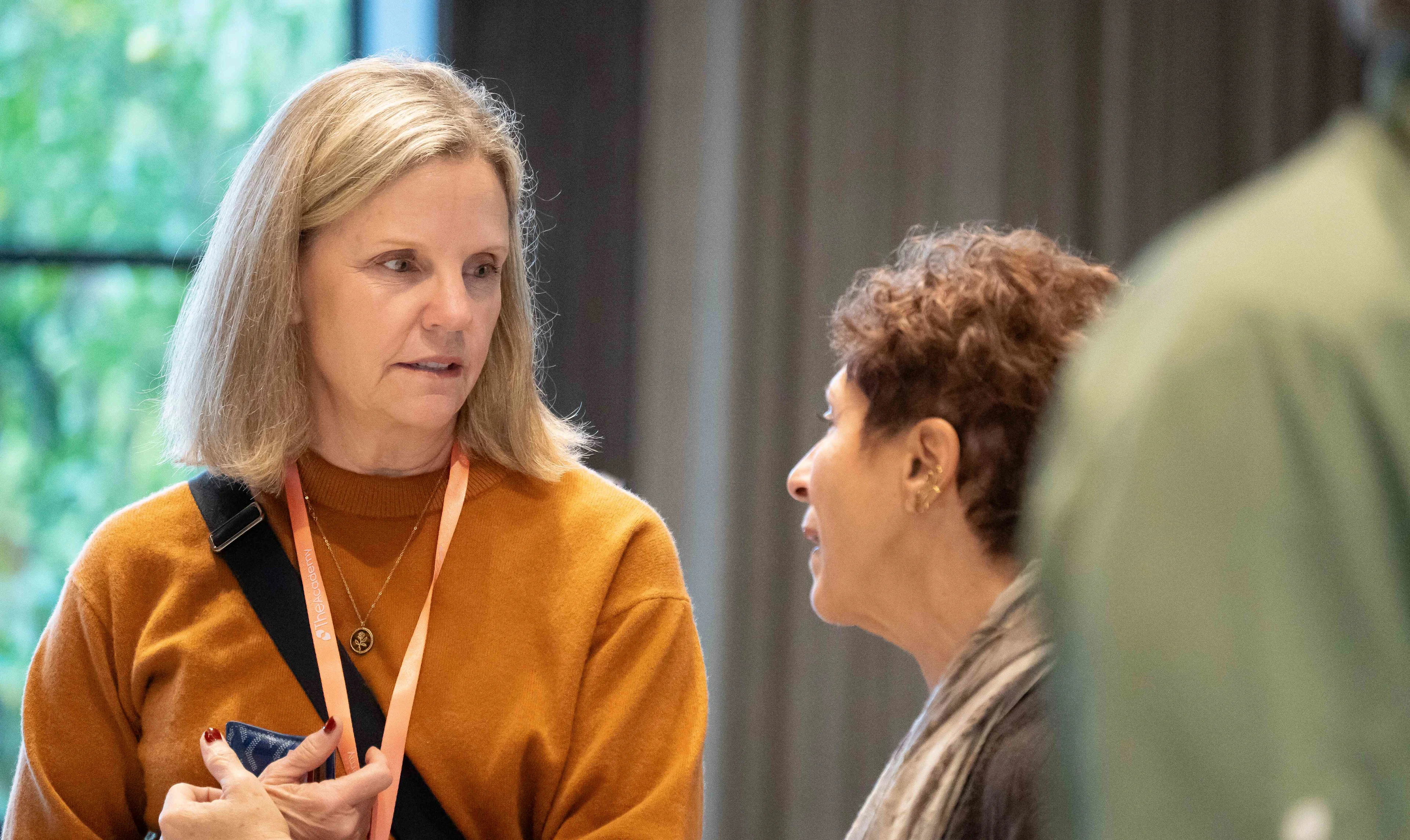 Two professionals hold a discussion during healthcare marketing conferences, standing inside a modern meeting space.