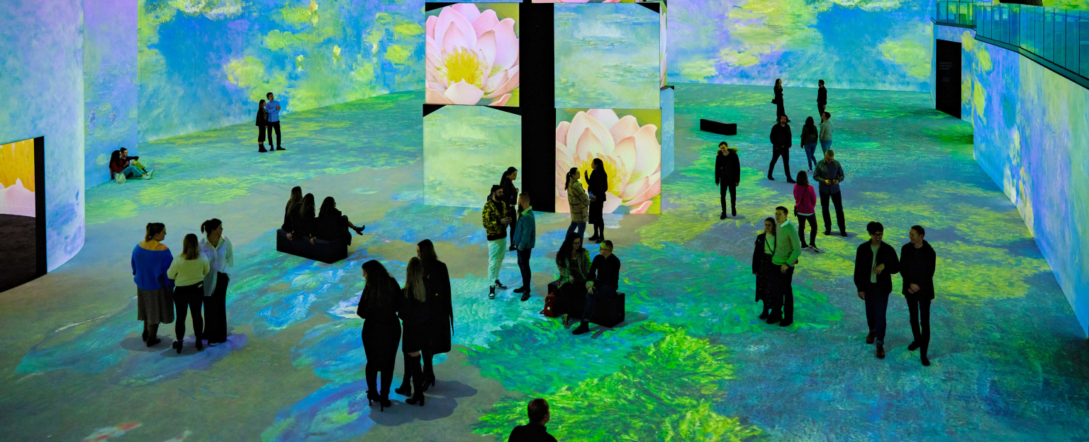 Overview of spread out crowd of people at THE LUME Melbourne with Monet display shown across all the screens. 