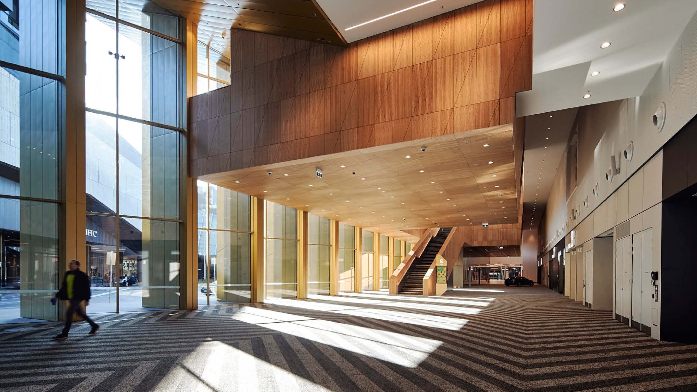 Looking down the corridor of the Convention Centre as natural light streams through the large windows. 