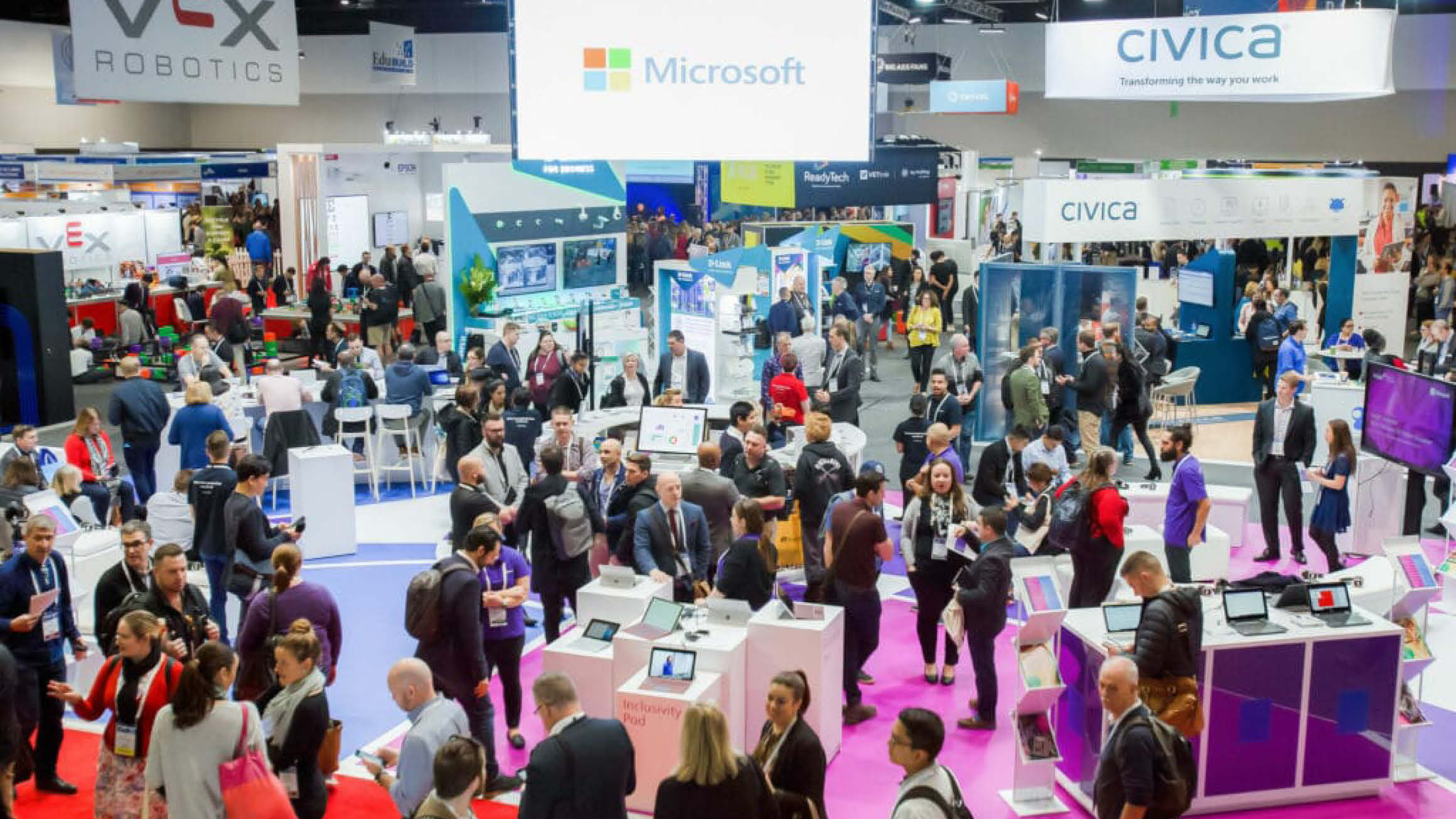 Over head view of an exhibition event with lots of people walking around exhibition booths. 