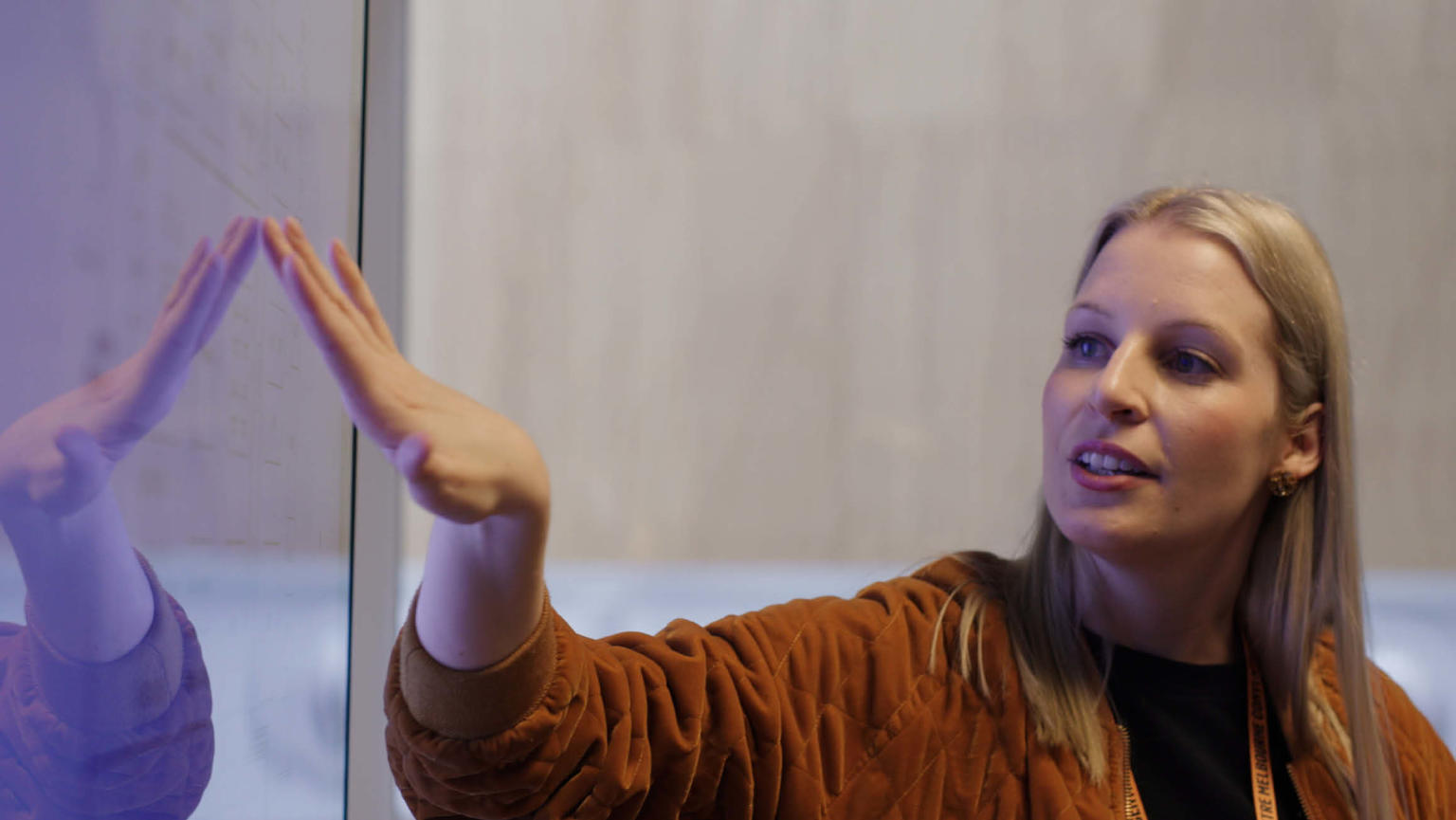 Anthea Fahey pointing at a whiteboard, engaged in a presentation to people off-camera.