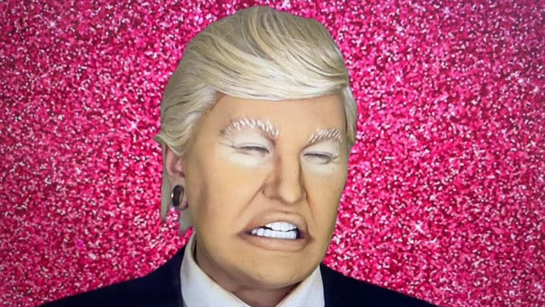 Donald Trump look a like making a smiling face with a sparkling pink background. 