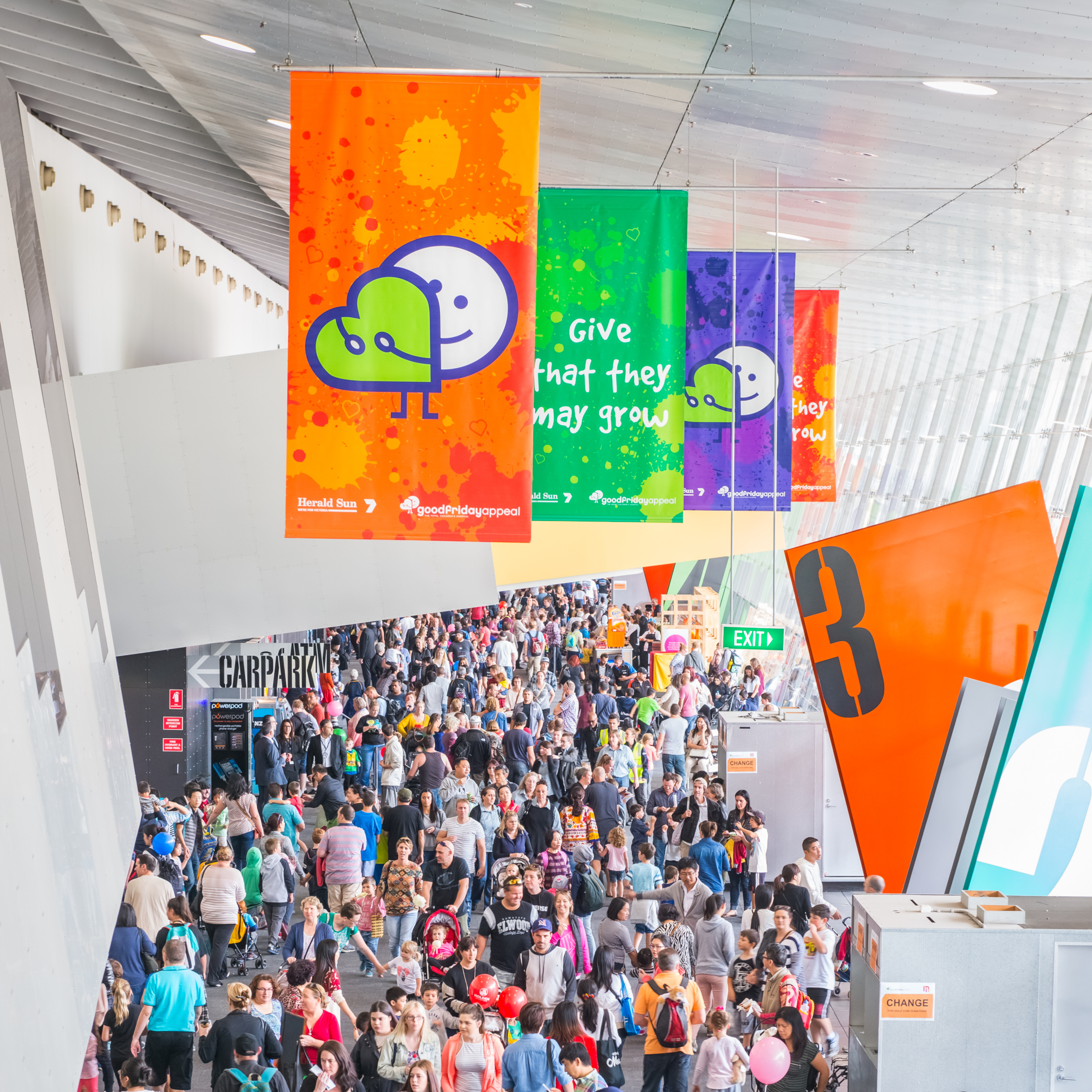 A large crowd walking around the foyer of the Melbourne Convention Centre.  