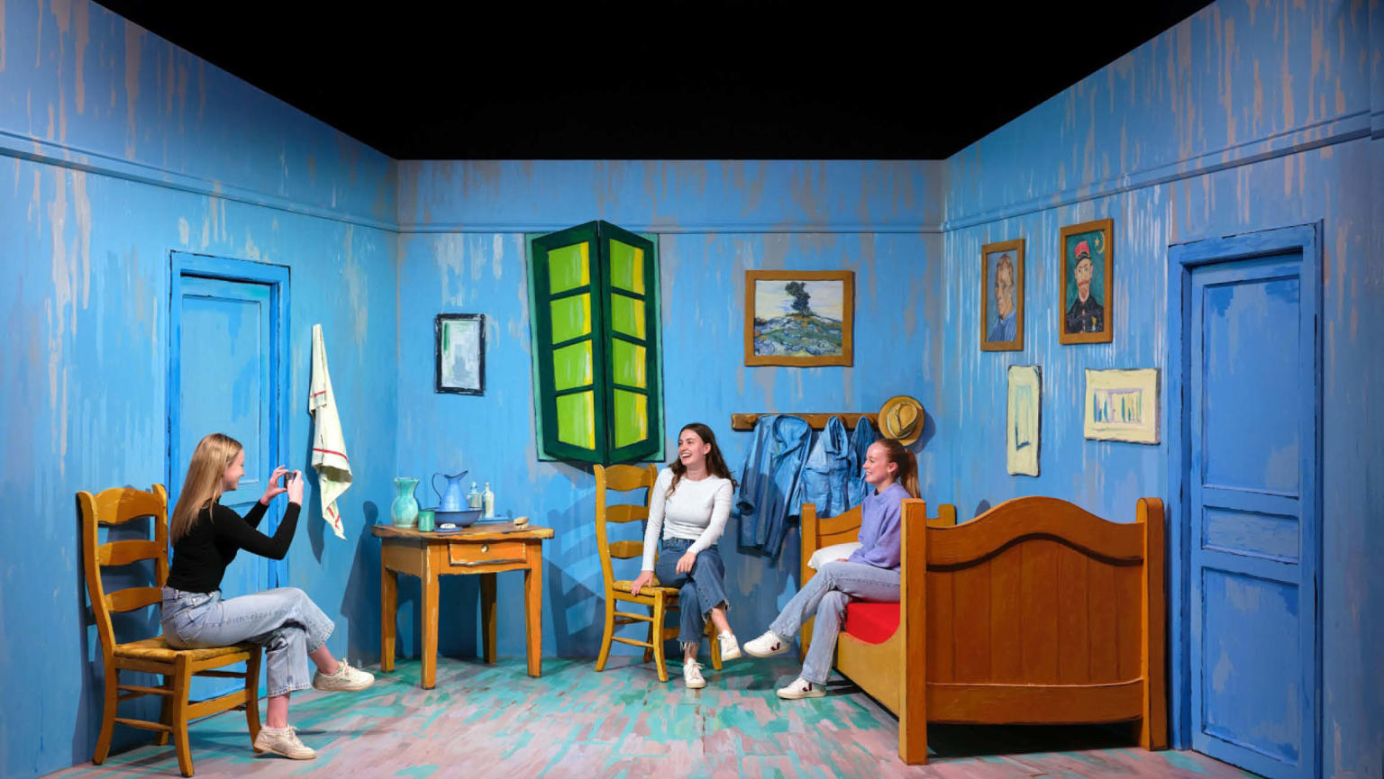 An image showing three women sitting in an animated cartoon room with one of the women taking an image on her phone of the other two. 