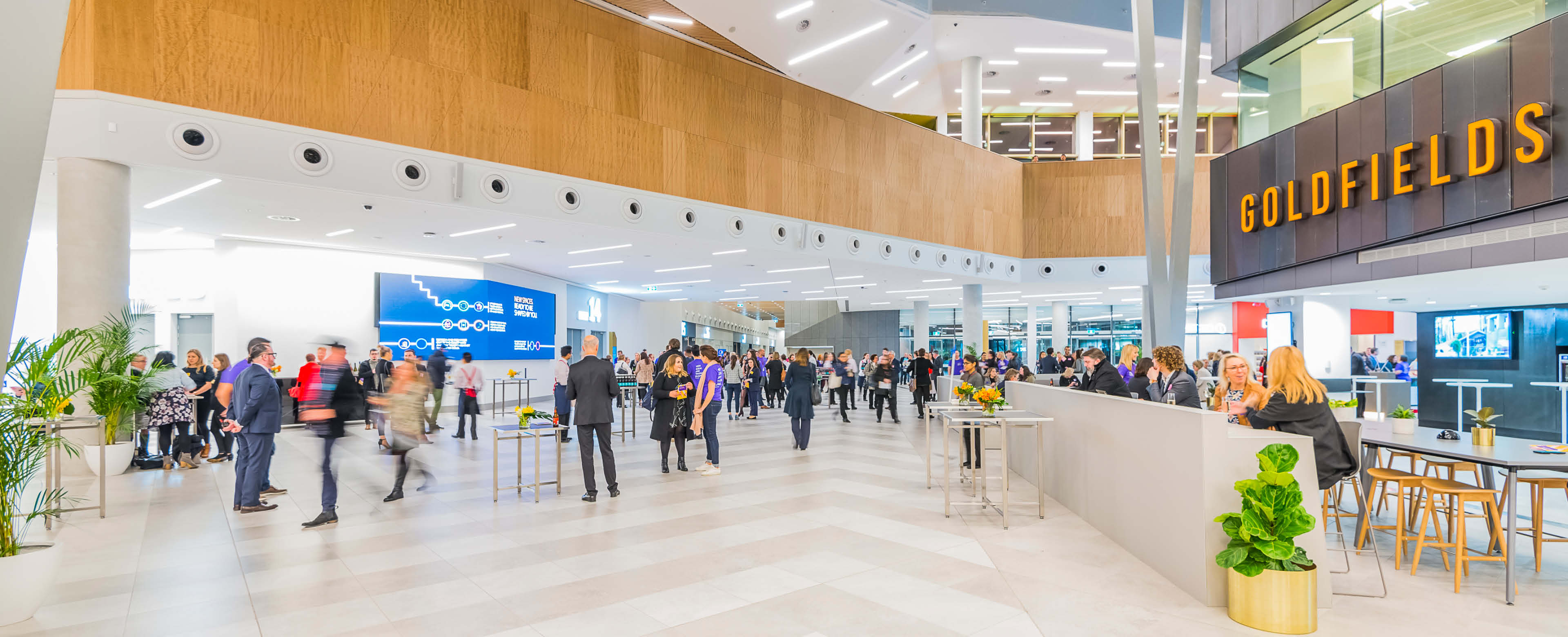 The new expansion foyer of MCEC (Melbourne Convention and Exhibition Centre) filled with numerous people standing and mingling.