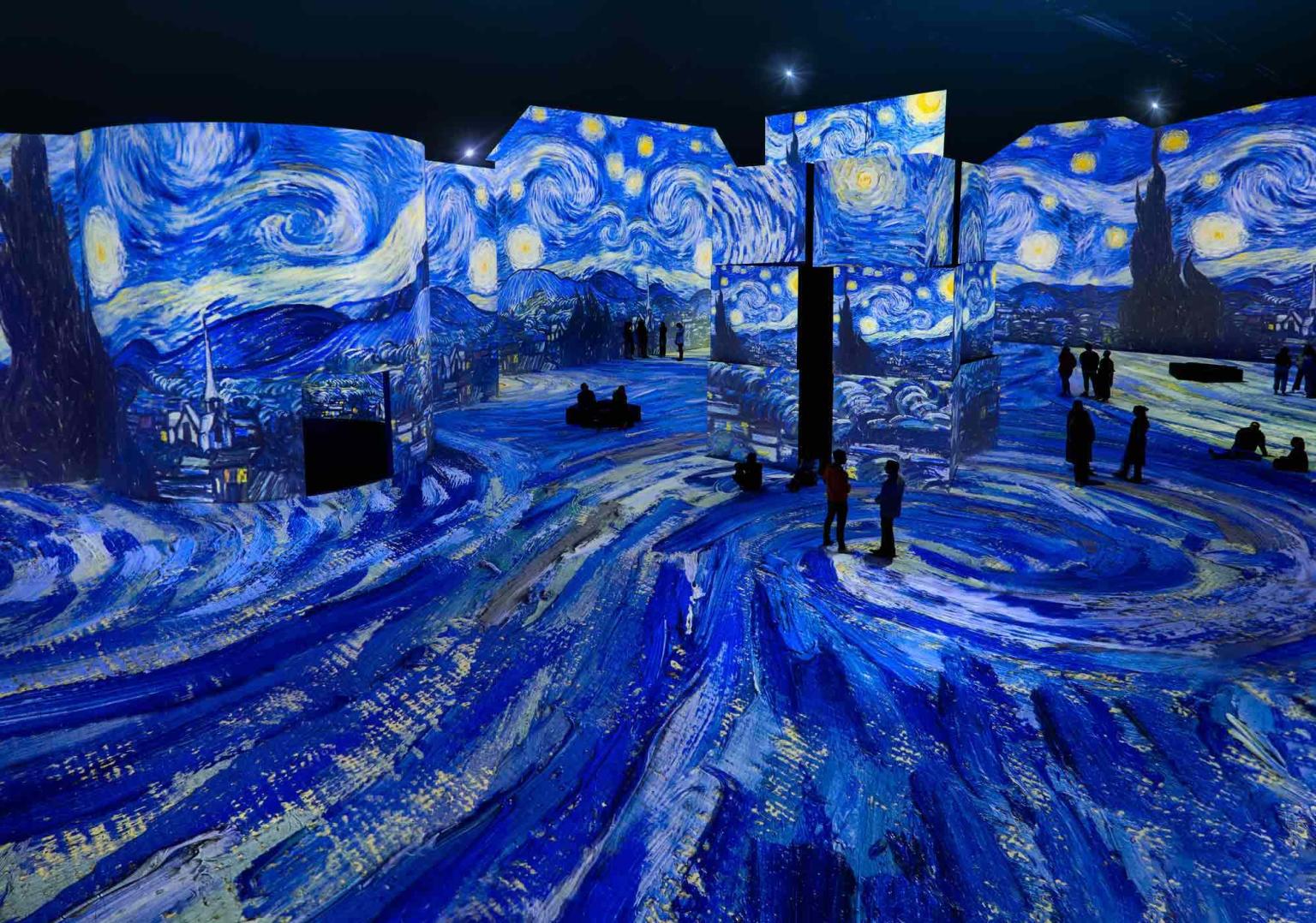 Van Gogh's starry night artwork displays across the THE LUME Melbourne with a few people scattered through out the room. 