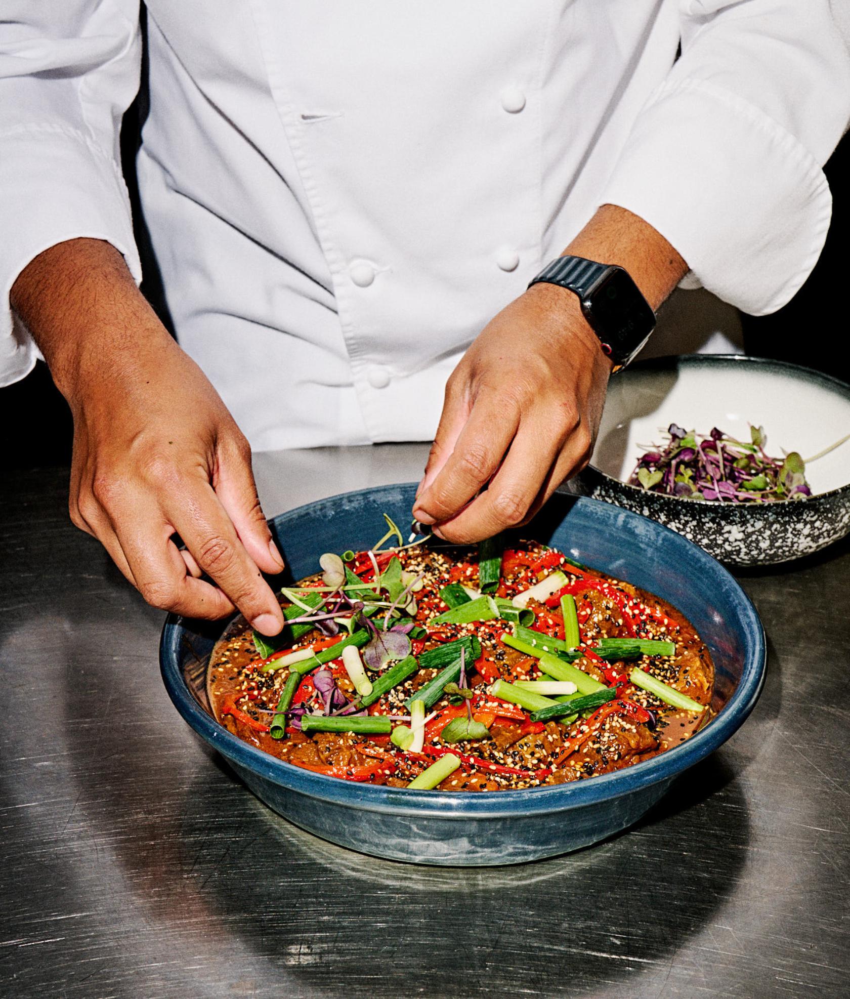 Pair of hands preparing a dish of sweet and sticky gochujang glazed Victorian beef brisket.