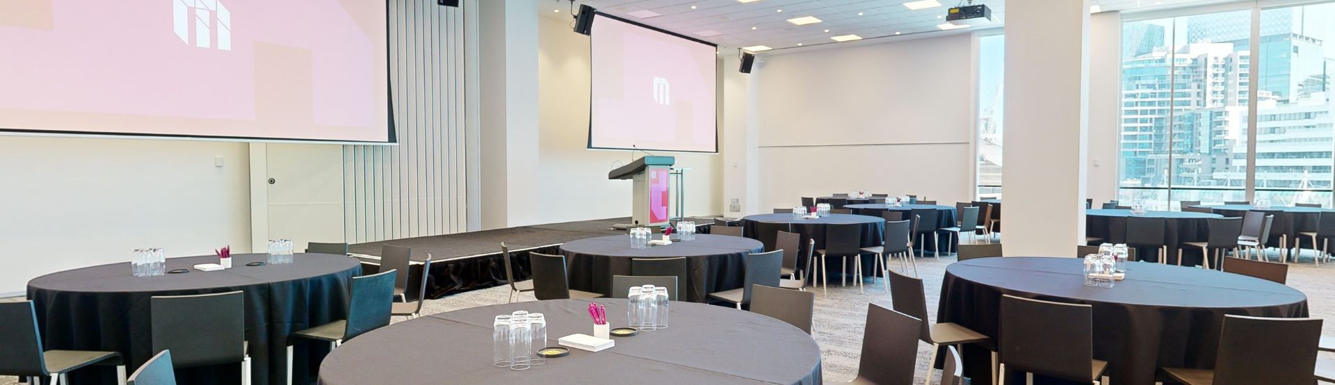 A spacious meeting room with neatly arranged tables and chairs, ready for a professional gathering.