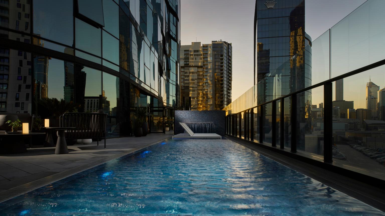 Shadow play exterior shot of the pool at dusk, includes city scape and exterior building 
