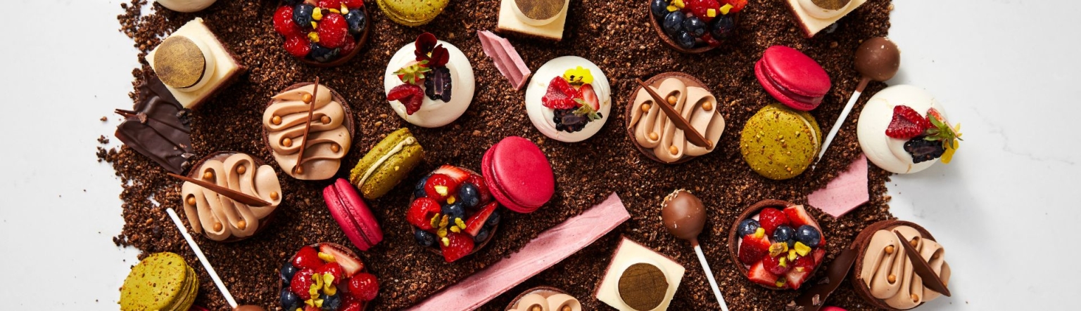 Birds eye of view of a selection of mini desserts that are scattered over a pile of chocolate shavings. 