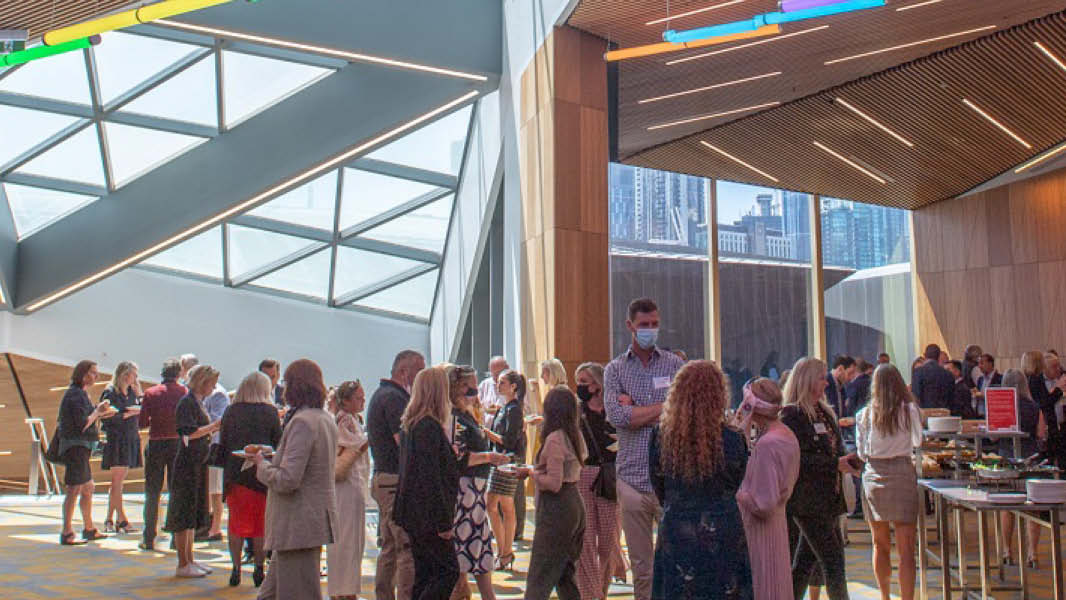 A lively foyer filled with a diverse crowd engaged in conversation and mingling. 